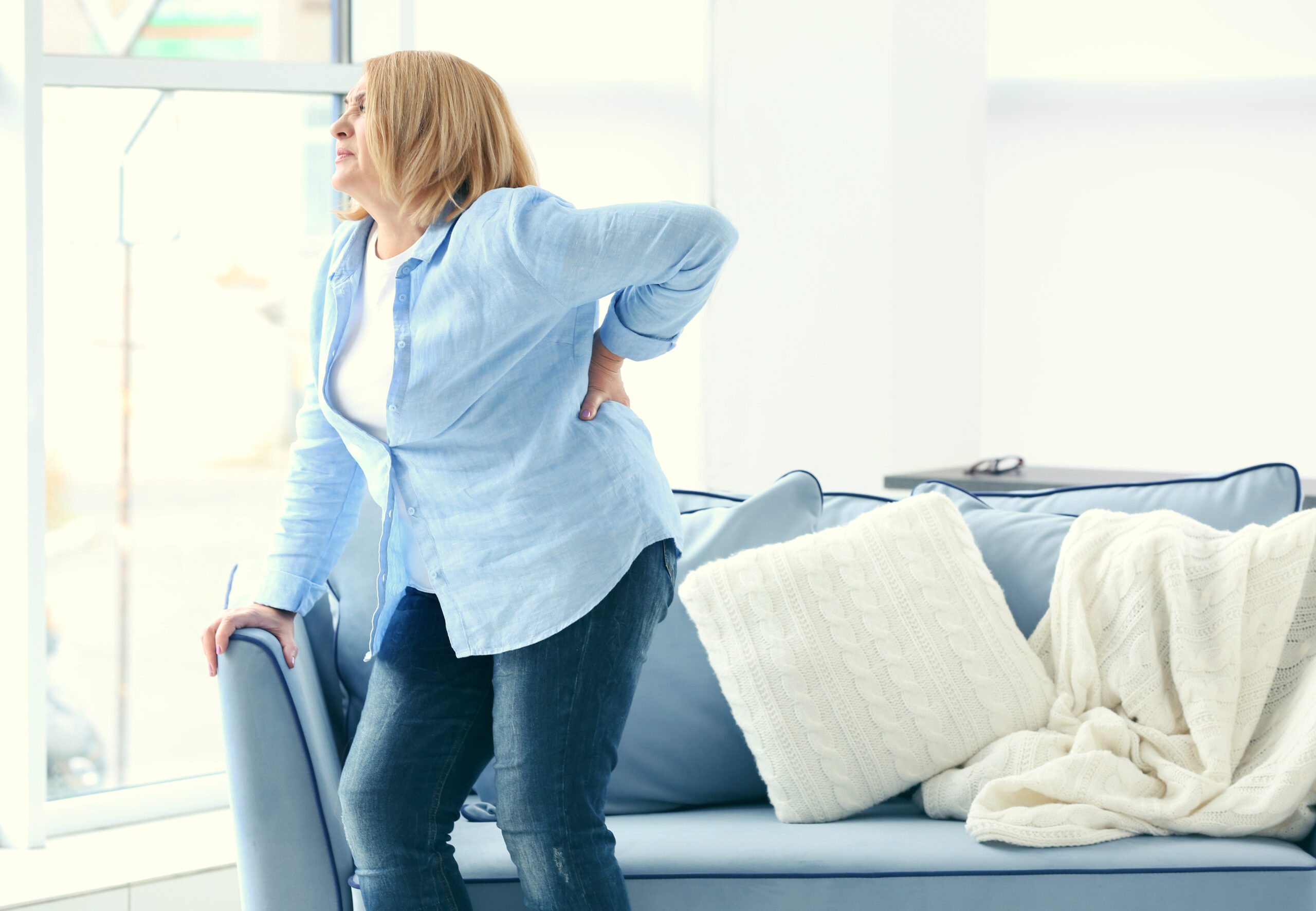 Senior woman suffering from backache at home chronic pain