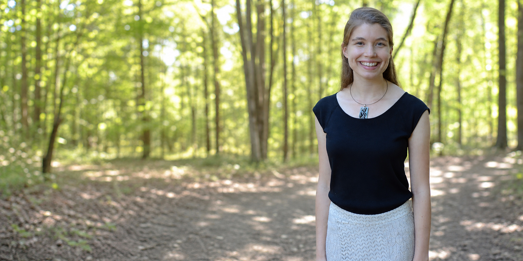 Dr. Jennifer Hampton standing in a sunlit wooded setting